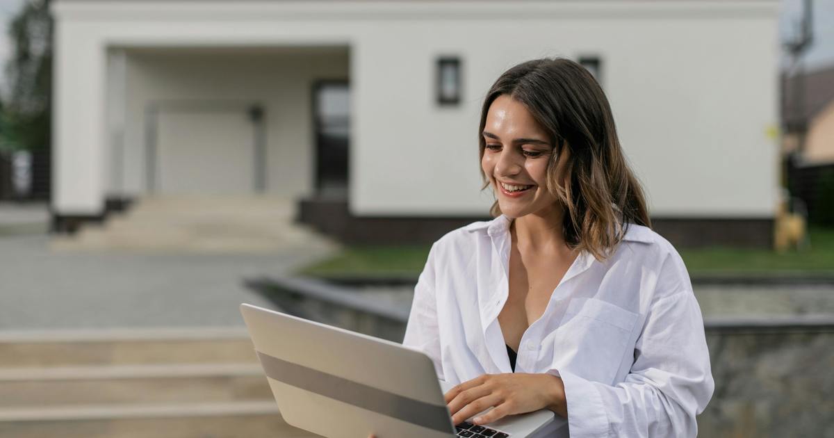 Smiling woman outside looking at laptop computer screen