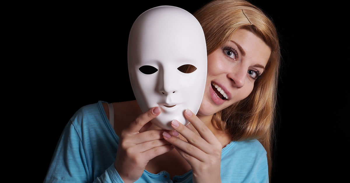 Smiling woman peering out from behind a mask