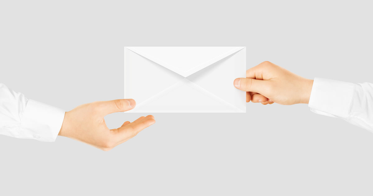 Close-up of a white letter-sized envelope being passed from one person's hand to another