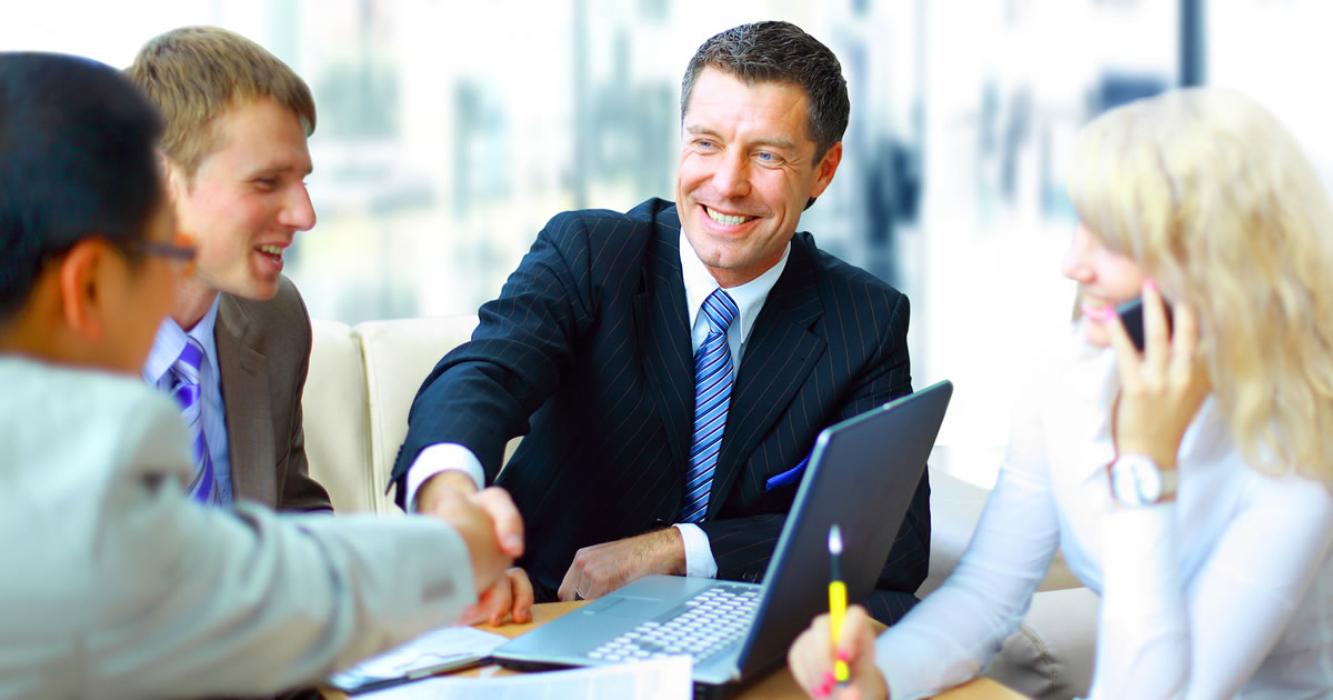 Smiling business people at a table shaking hands