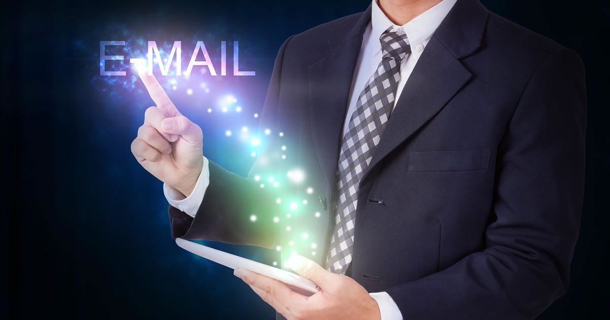 Businessman holding tablet with email icons floating out like magic from the internet connection