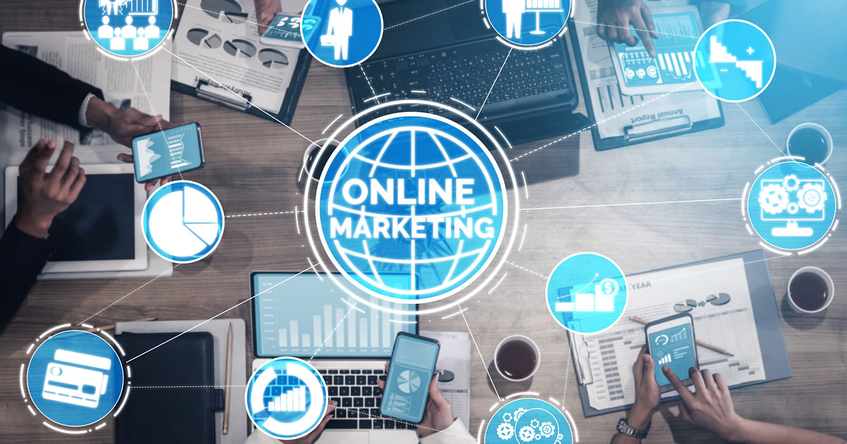 The words Online Marketing surrounded by digital marketing icons over an image of businesspeople using electronic devices