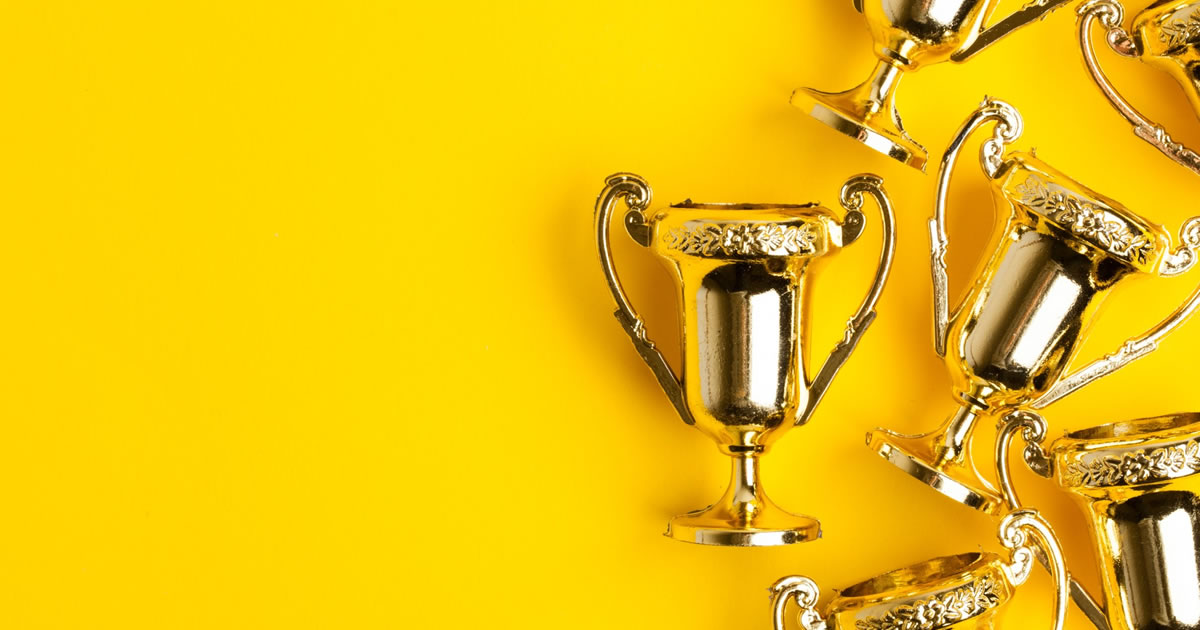 Gold winners trophies on a bright yellow background