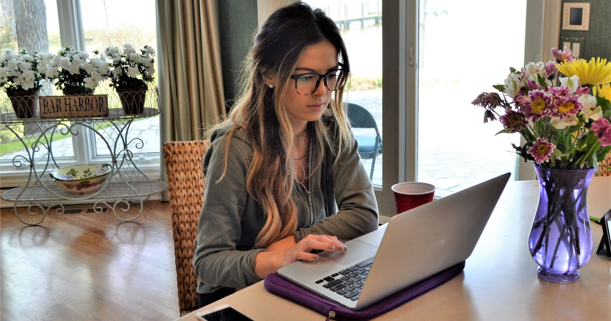 Millennial writing on her laptop in the kitchen