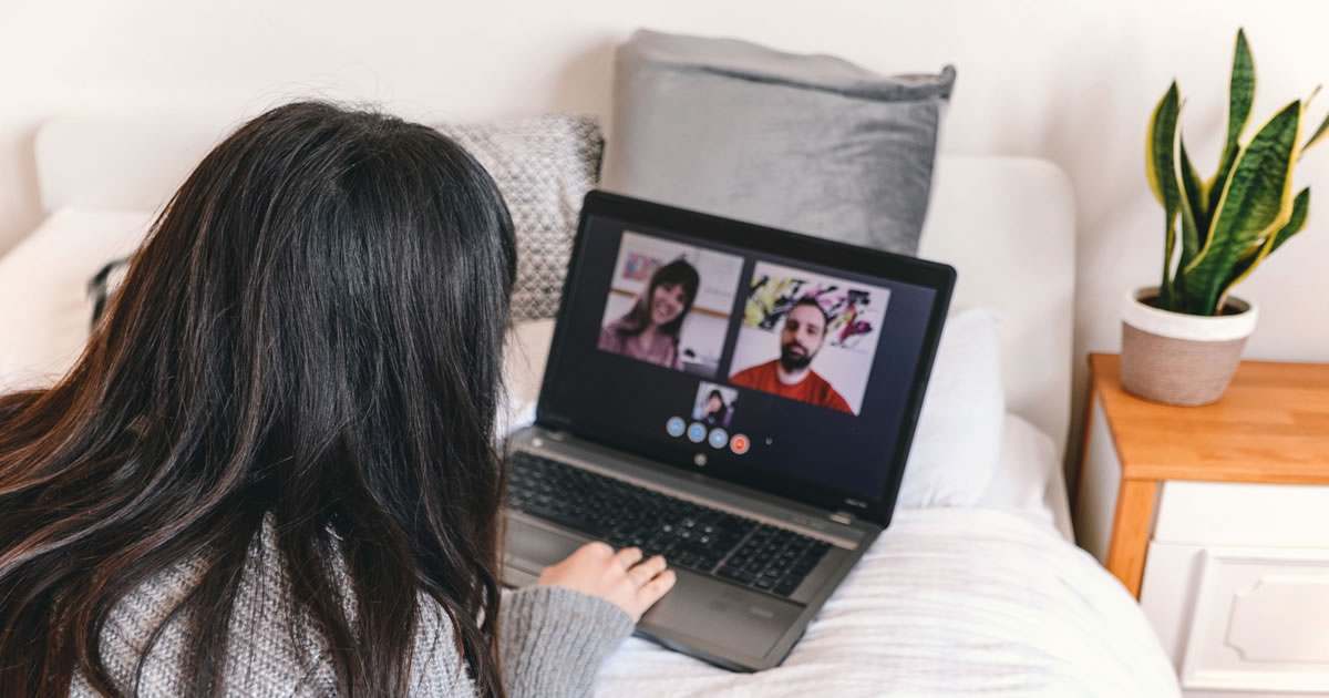 Young woman video chatting in virtual meeting on laptop at home