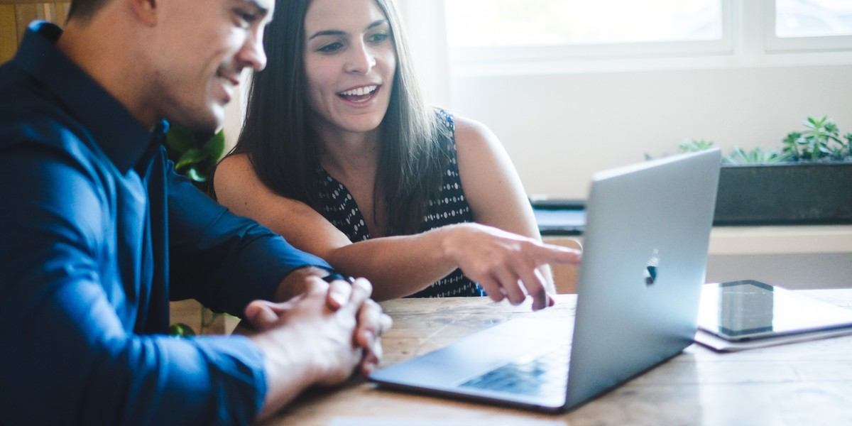 Woman giving positive feedback on computer to man