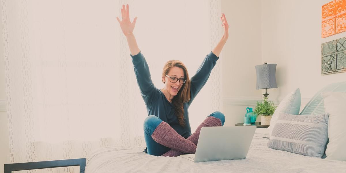 Excited woman with her arms up looking at her laptop
