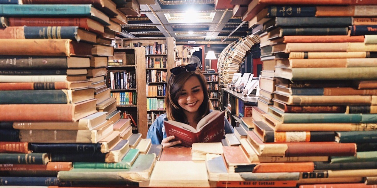 Smiling woman writer surrounded by stacks of books