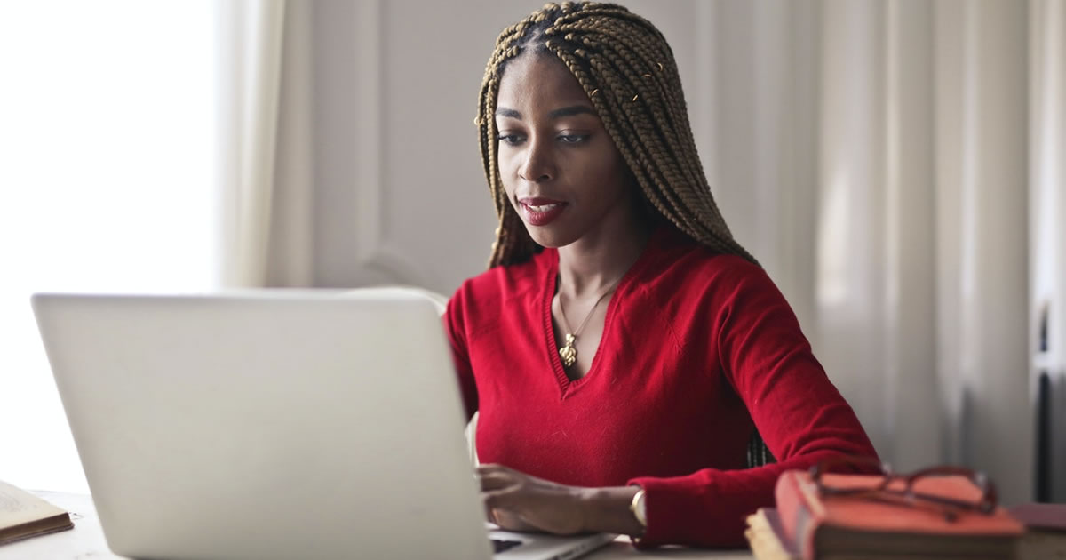 Woman in red top writing on her laptop sitting at a table