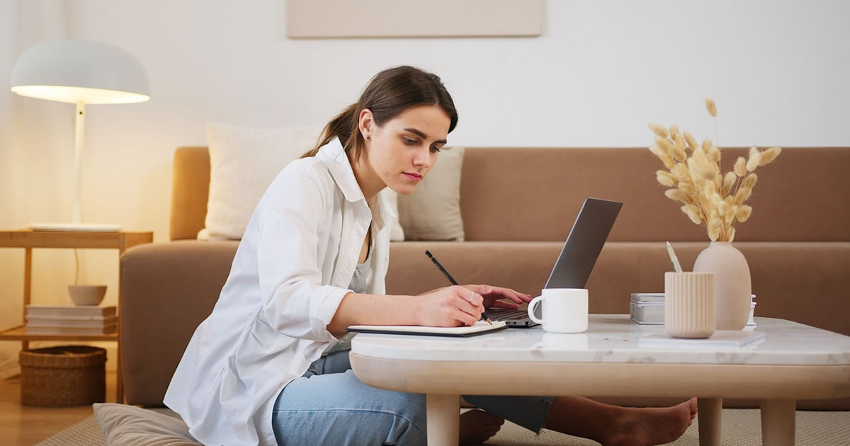 Young woman reviewing laptop and making notes on checklist