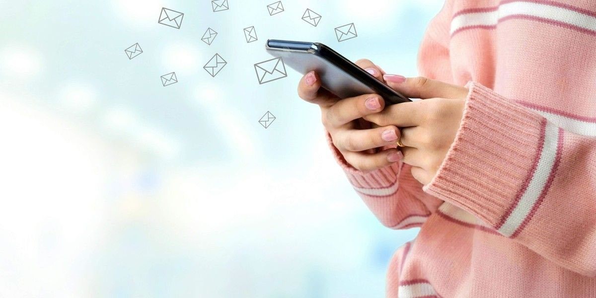 Close-up of a woman's hands using a smartphone with email envelope icons surrounding it