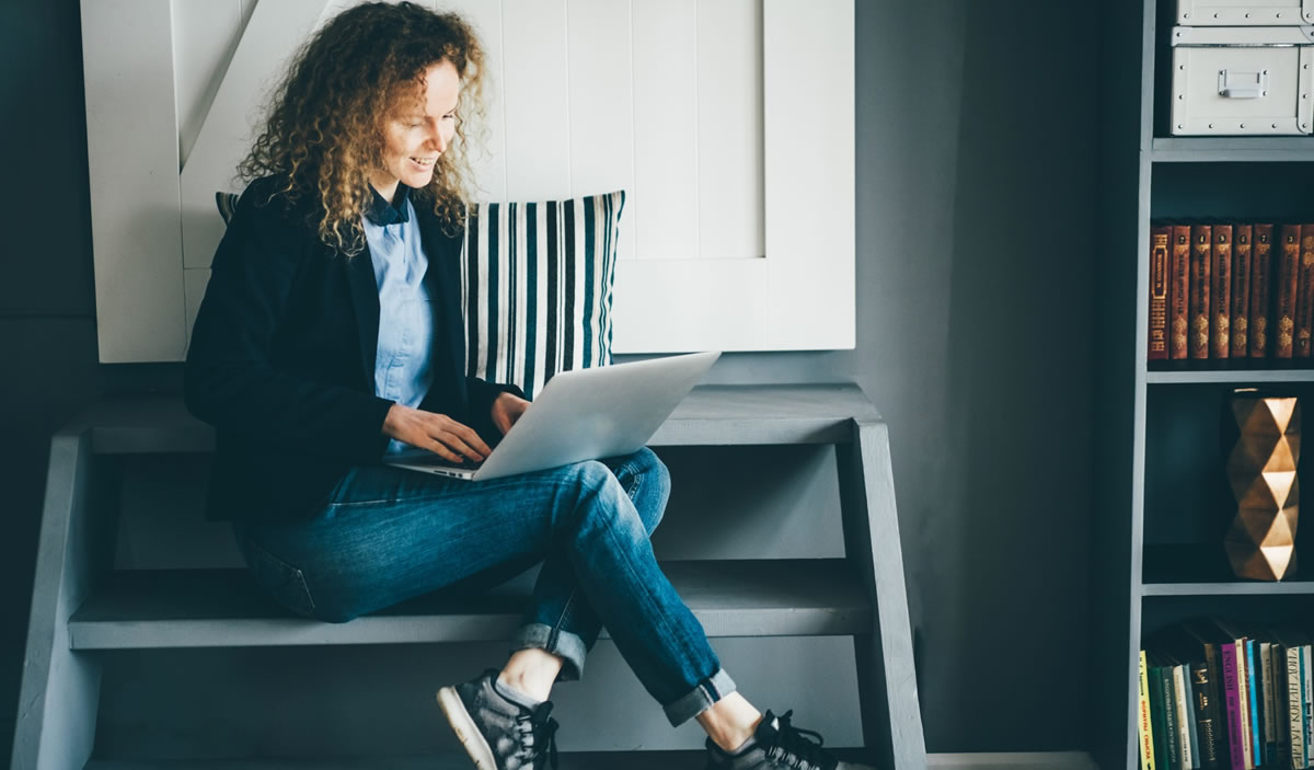 Young woman writing on laptop in apartment