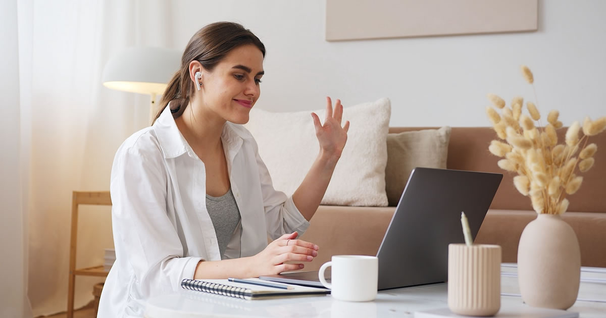 Cheerful woman writer having video meeting via laptop