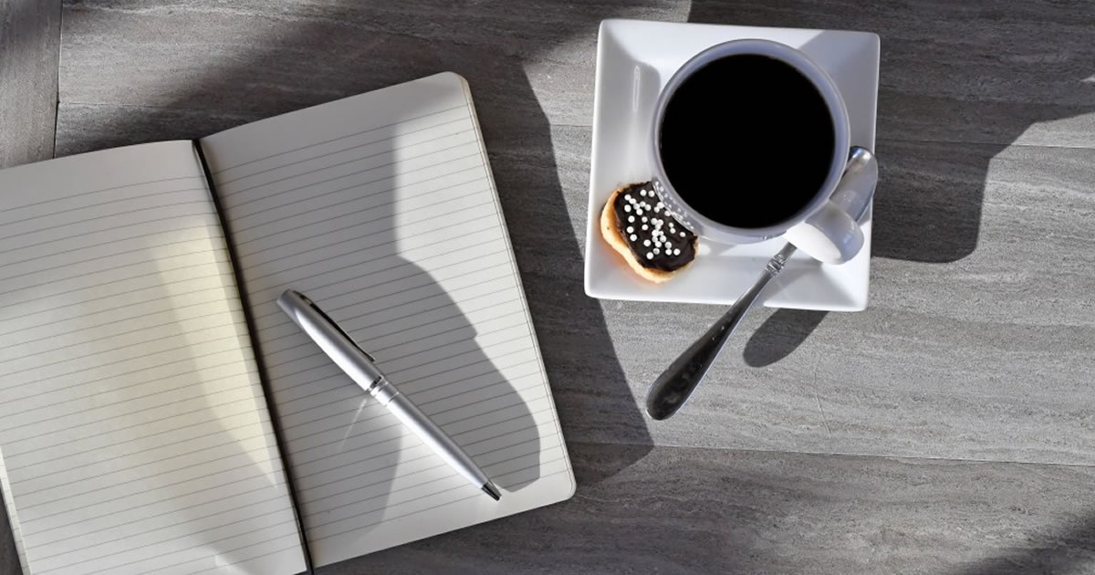 Blank journal, pen, pastry, and full coffee cup