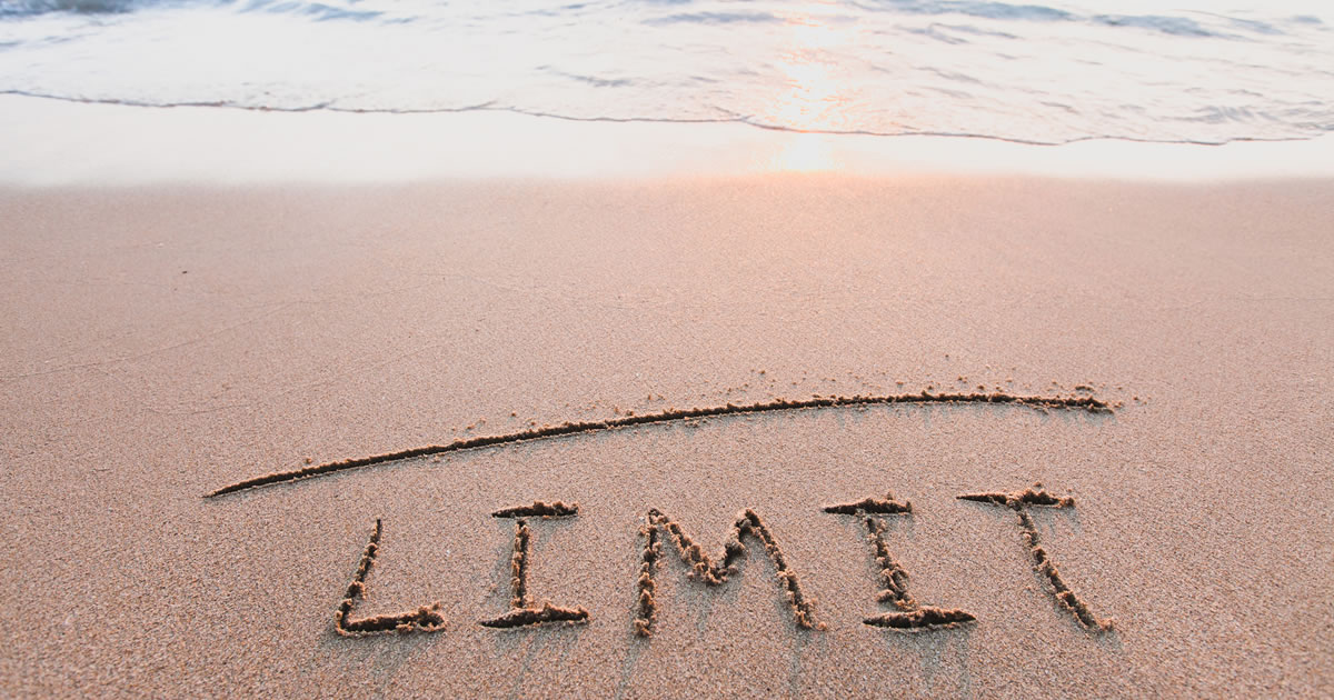 A line and the word limit drawn in the sand at the beach