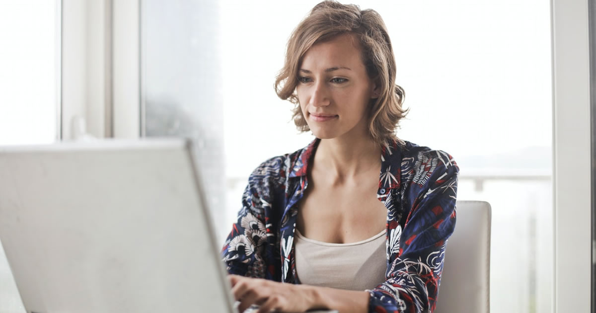 Woman writing on laptop at desk