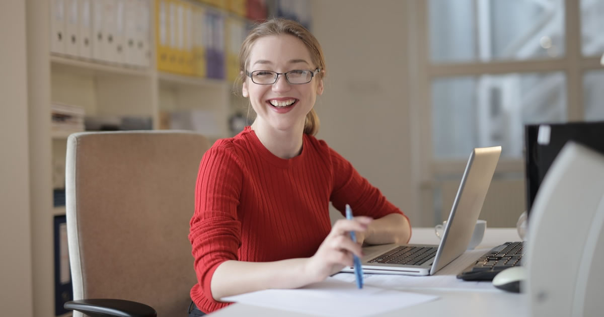 woman smiling at desk in front of computer