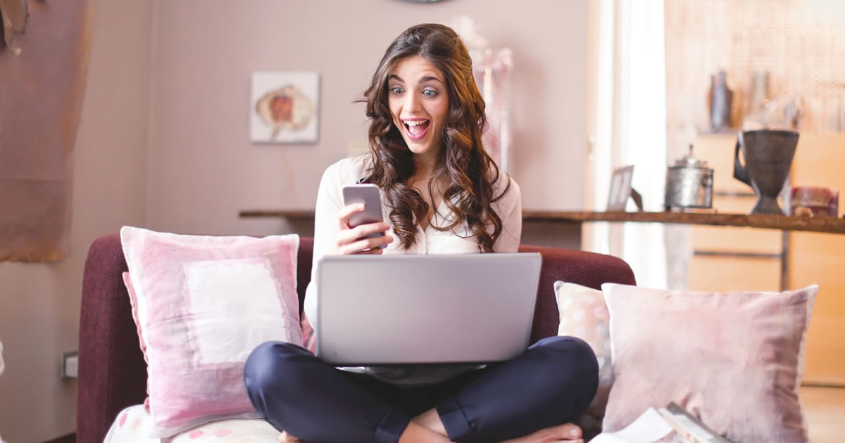 woman writer sitting on couch with laptop and smartphone