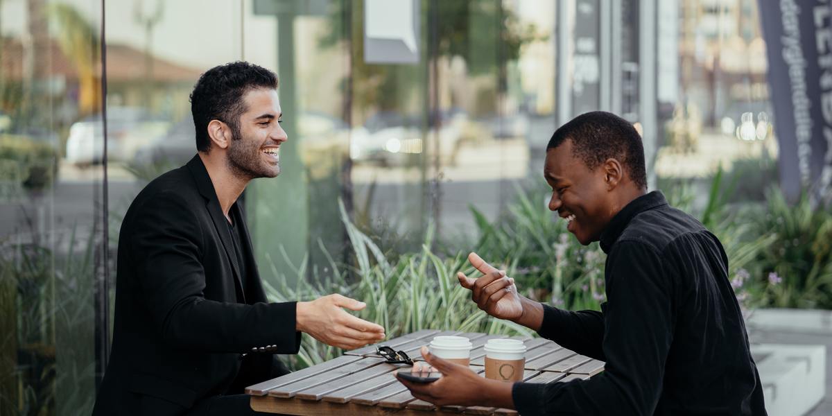 two male writers networking over coffee at outside cafe