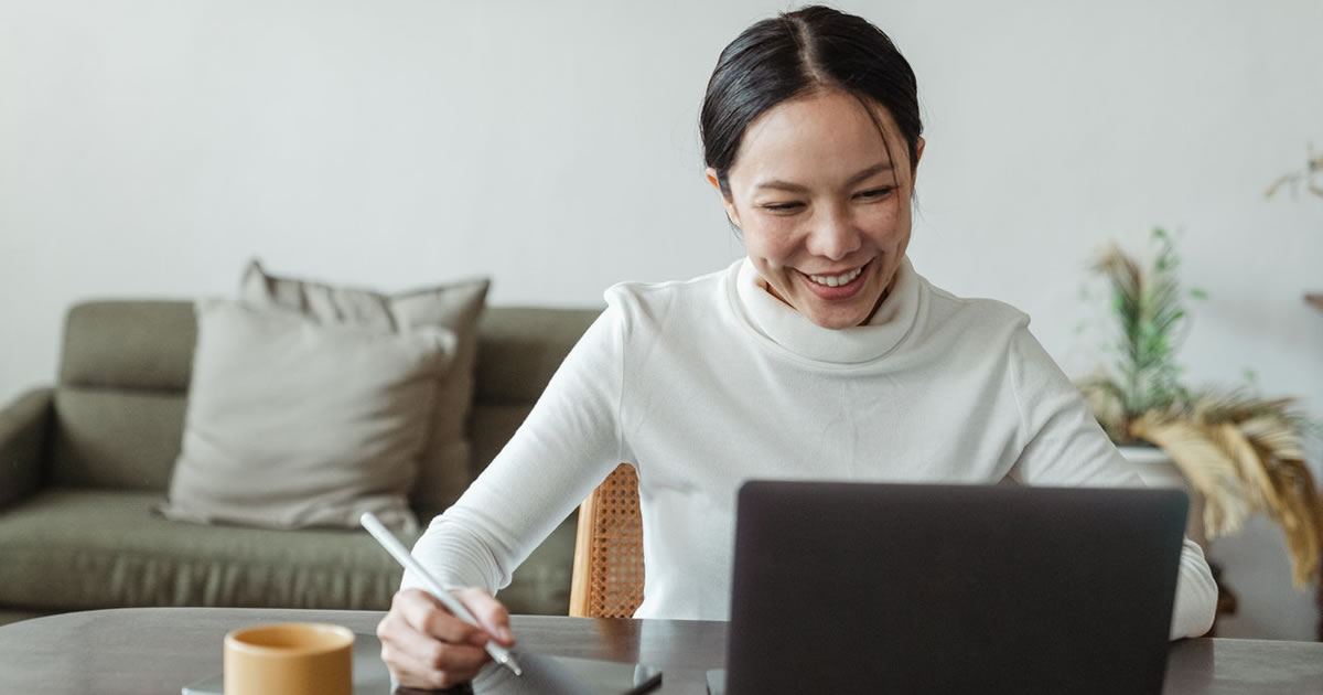 woman working on laptop and making notes on checklist