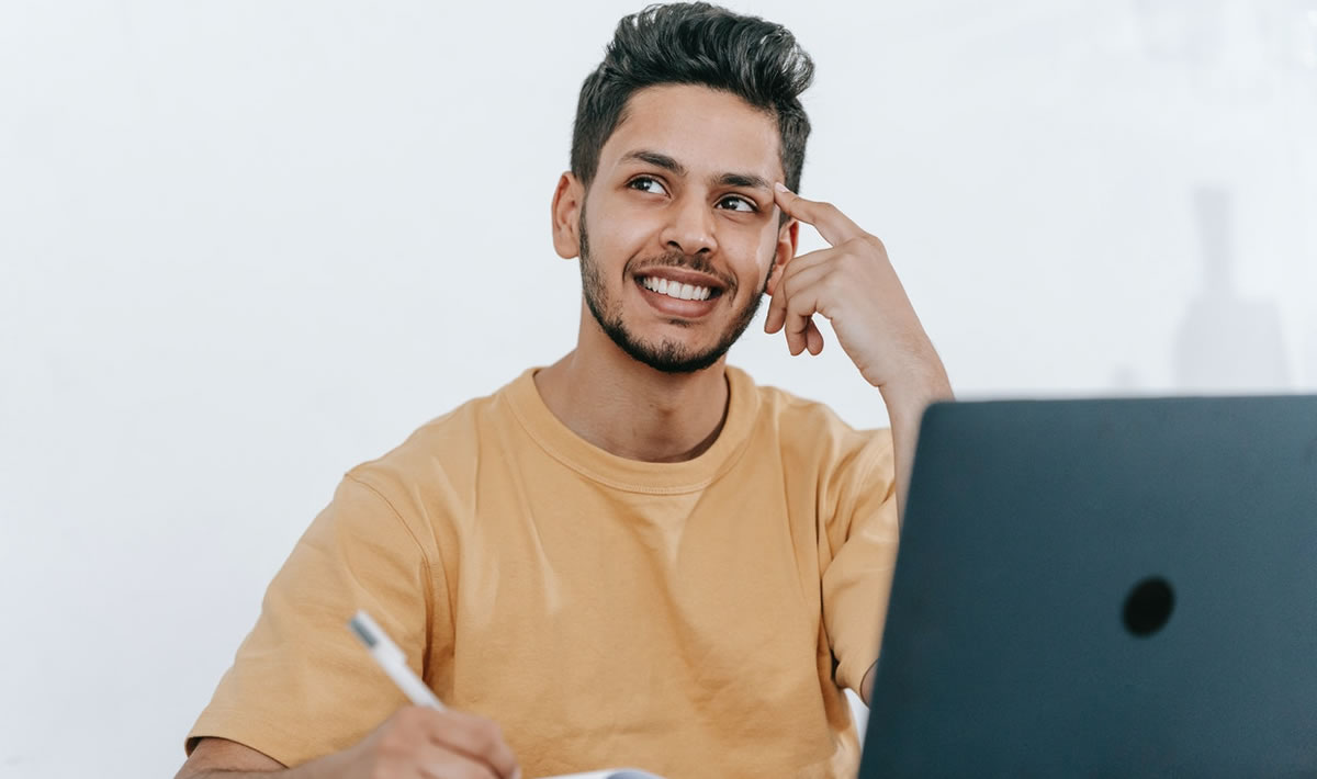 happy writer thinking while working at a desk with a laptop