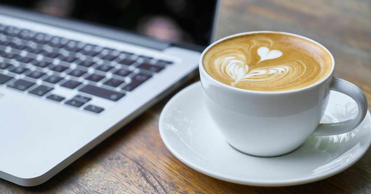 laptop and coffee mug containing heart outline