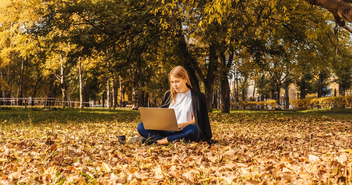 Young businesswoman working with laptop in nature with coffee