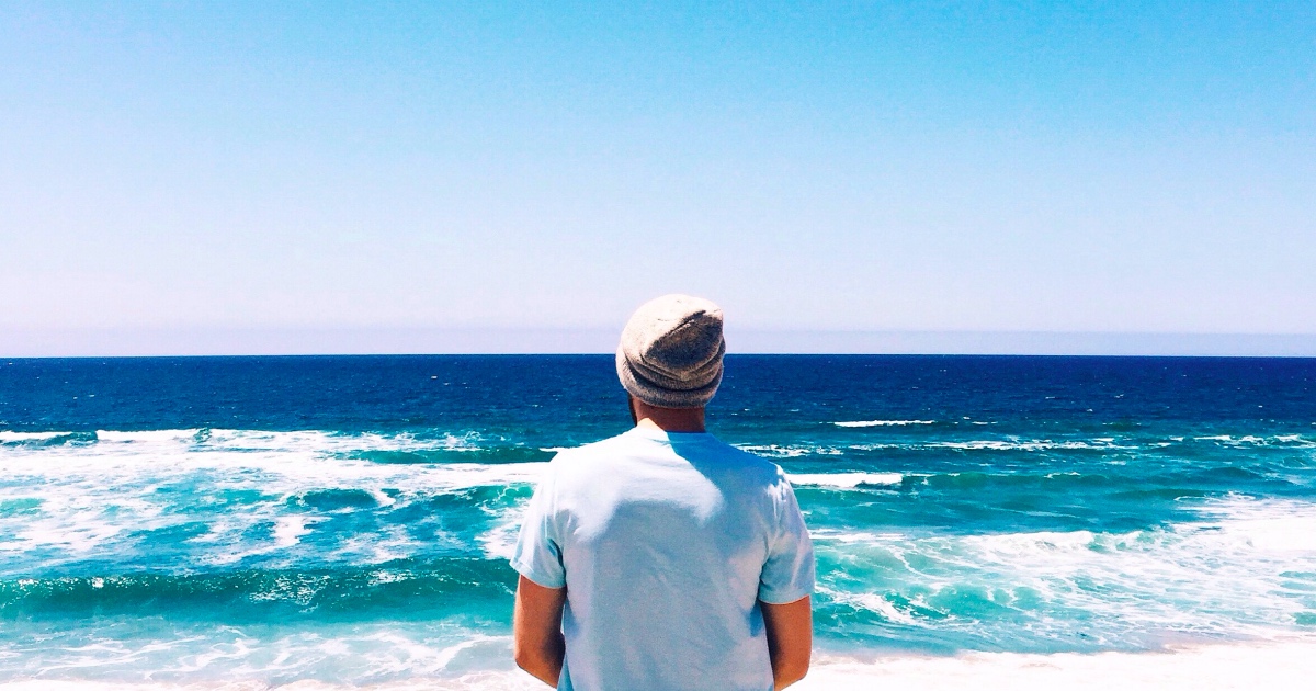 Man with his back to the camera looking at the ocean