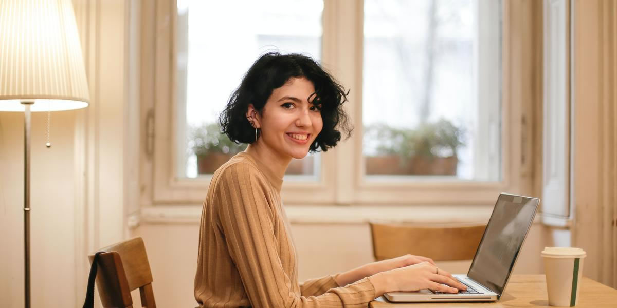 Smiling woman sitting at desk using laptop computer