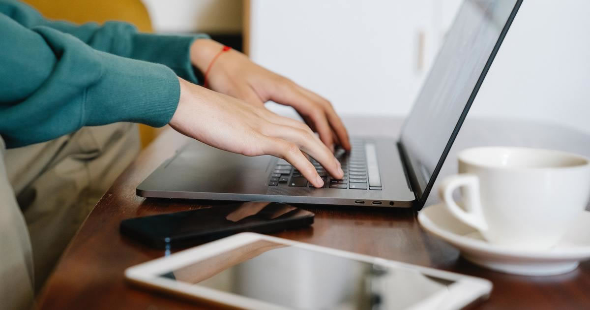 Closeup of hands typing on laptop keyboard on coffee table