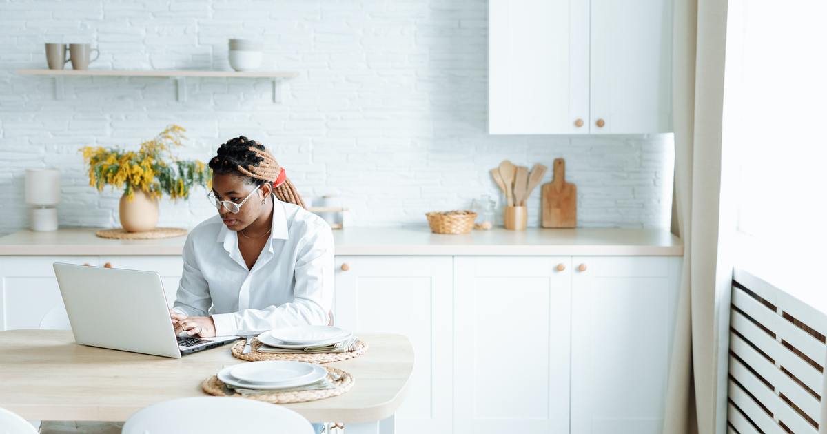 Woman typing on a laptop in the kitchen