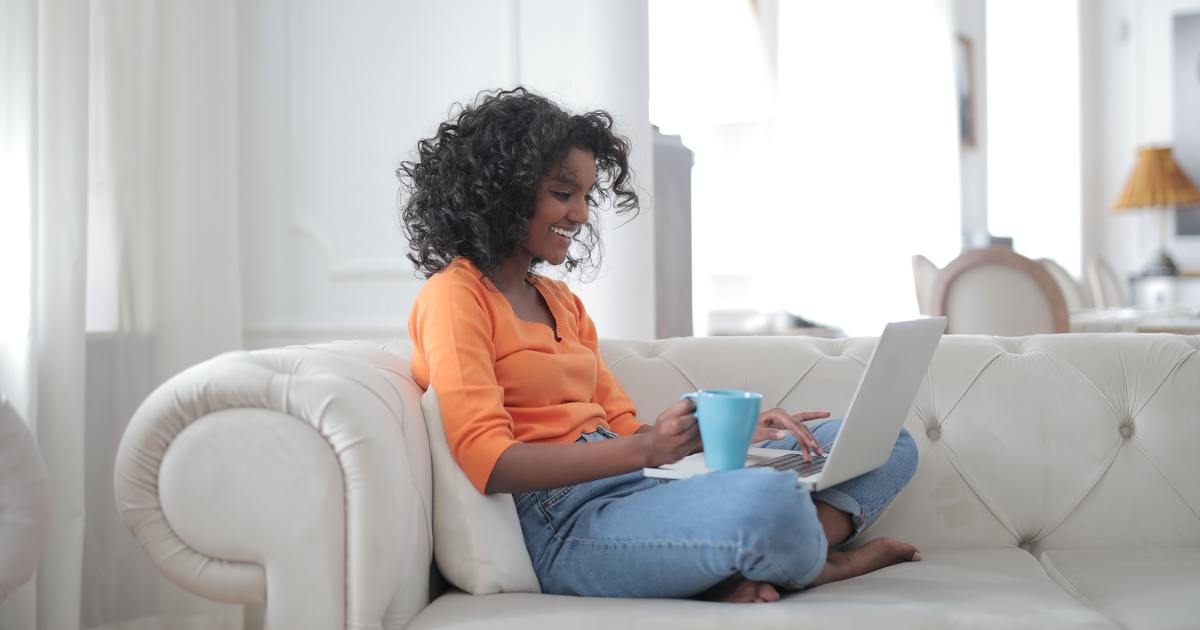 Writer sitting on couch with laptop and coffee mug