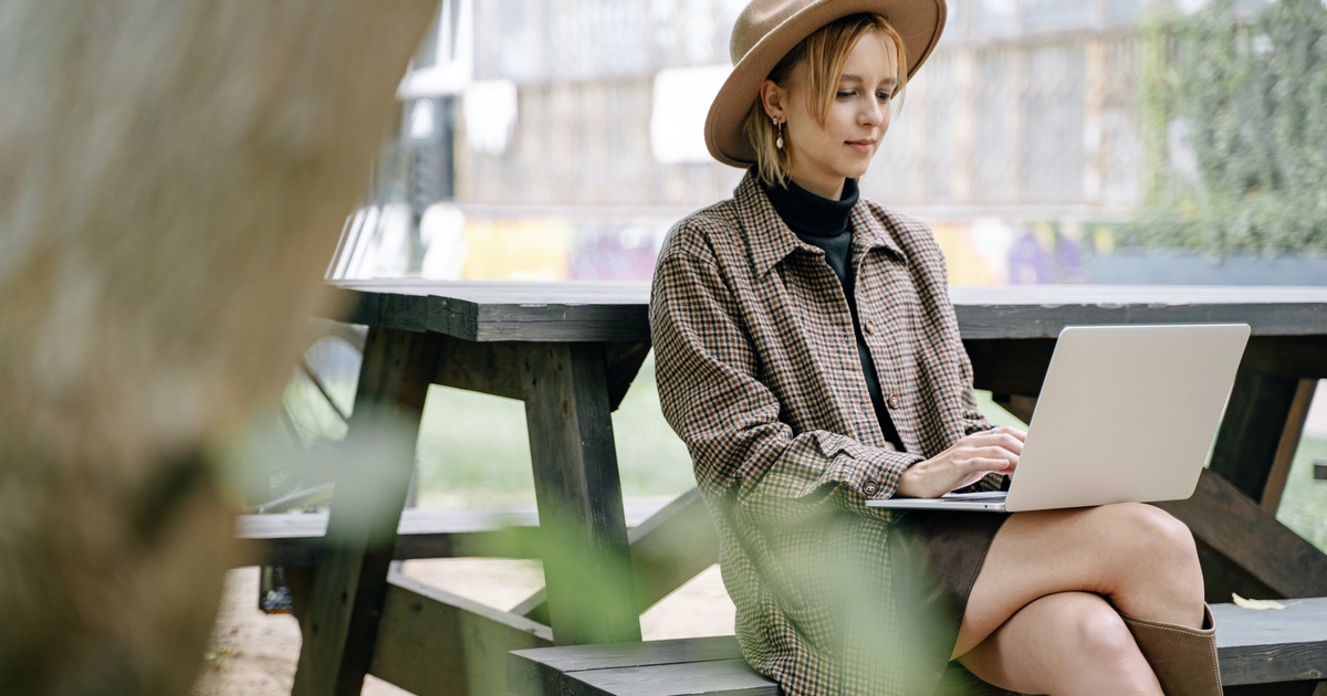 Writer sitting outside at a picnic table with a laptop