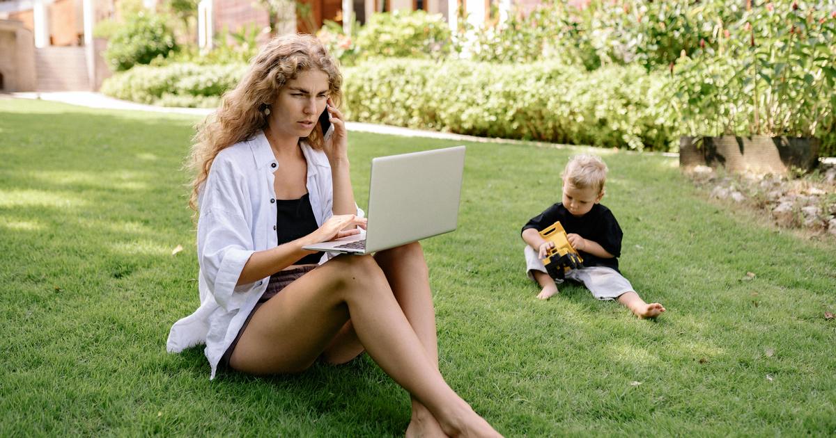 Mom sitting in yard with laptop and child