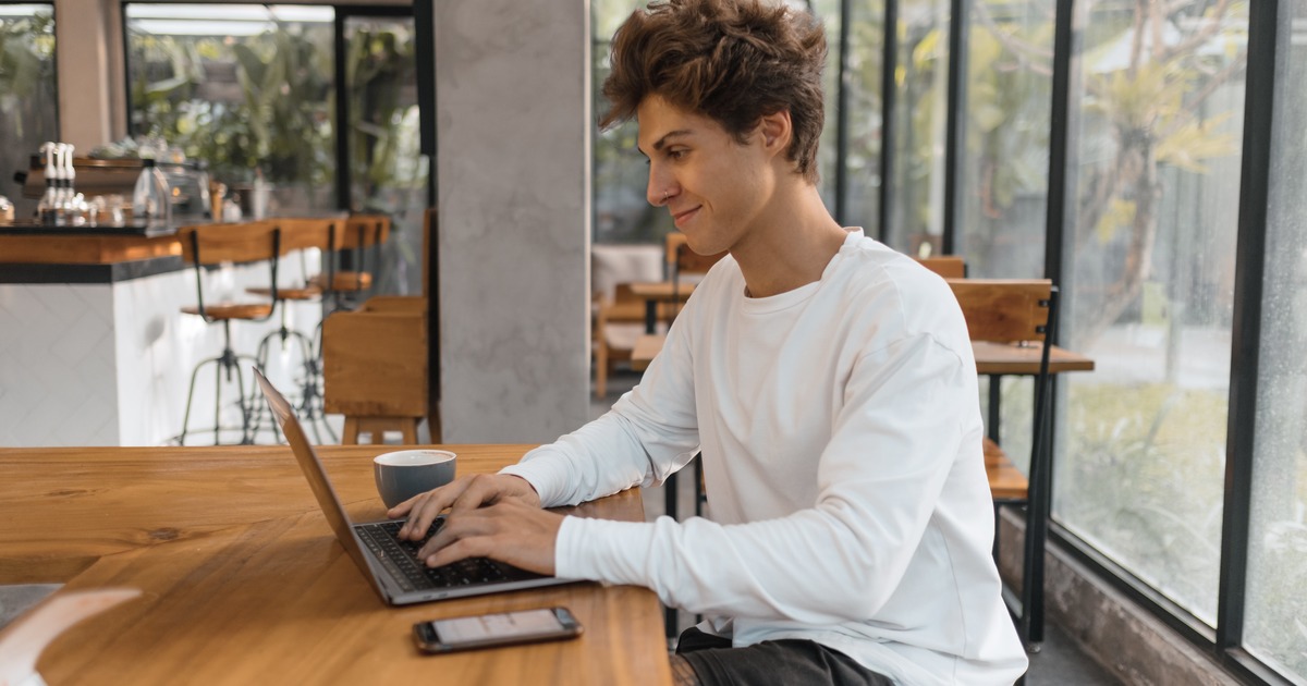 Writer in a coffee shop typing on a laptop