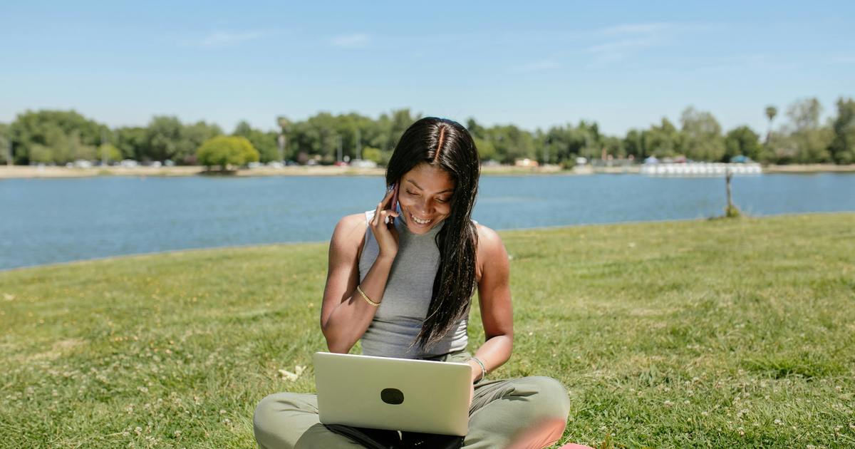 Writer sitting outside with laptop, talking on the phone