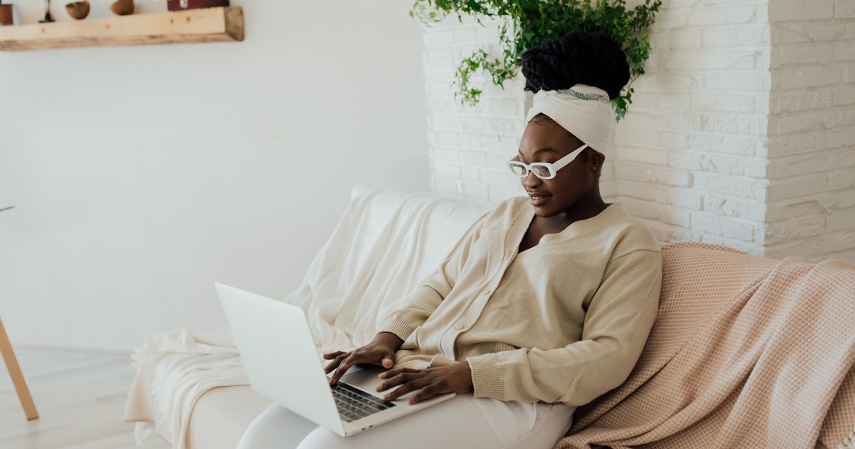 Writer sitting on couch typing on laptop