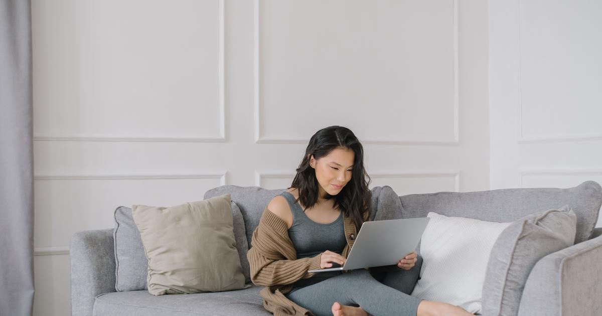 Woman sitting on couch typing on laptop