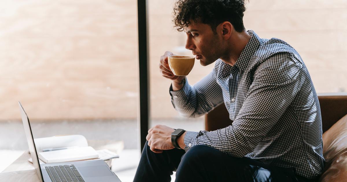 Writer drinking coffee while looking at laptop