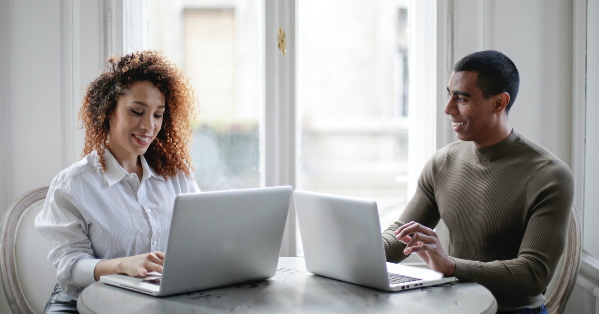 Two writers sitting at a table with laptops