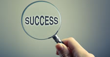 Hand holding magnifying glass over the word success