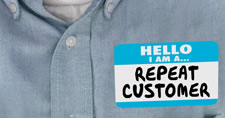 Close-up of name tag displaying Hello I Am a Repeat Customer